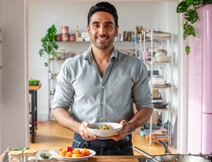 Dr Rupy Aujla holding a bowl of food in his kitchen